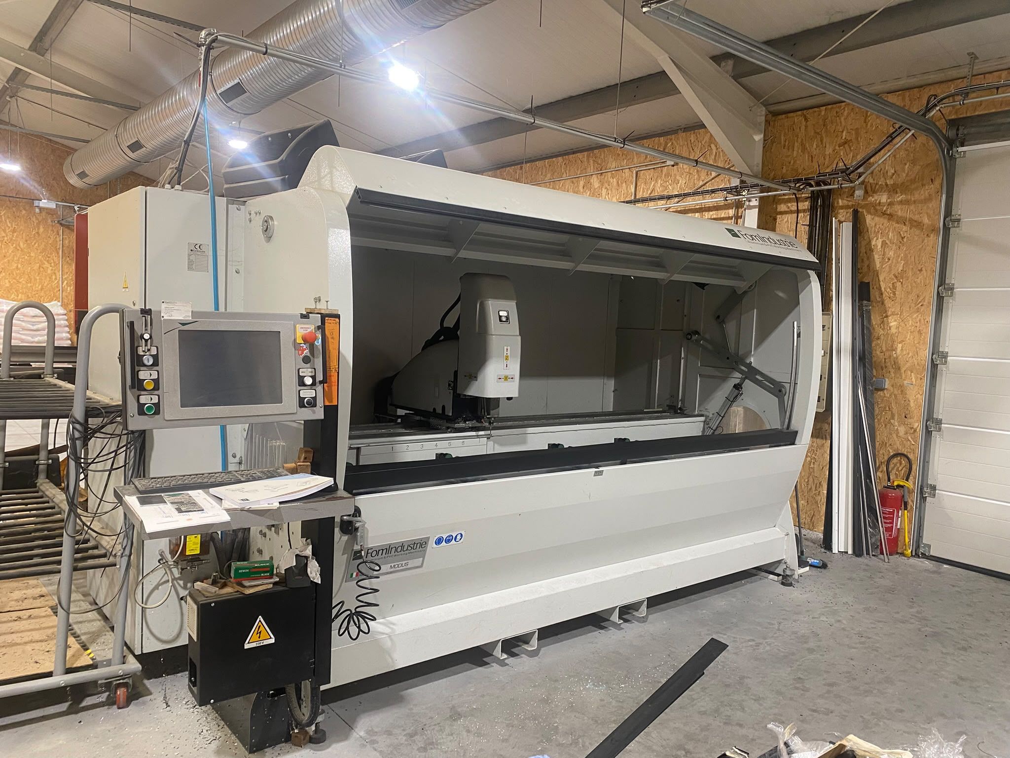 Machine d'usinage des profilés FOM Industrie Modus, pupitre de commande au premier plan, dans l'atelier AlexAlu